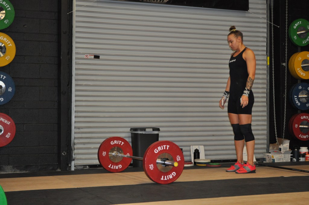 Standing behind olympic weightlifting bar. Shows visualization before attempting lift